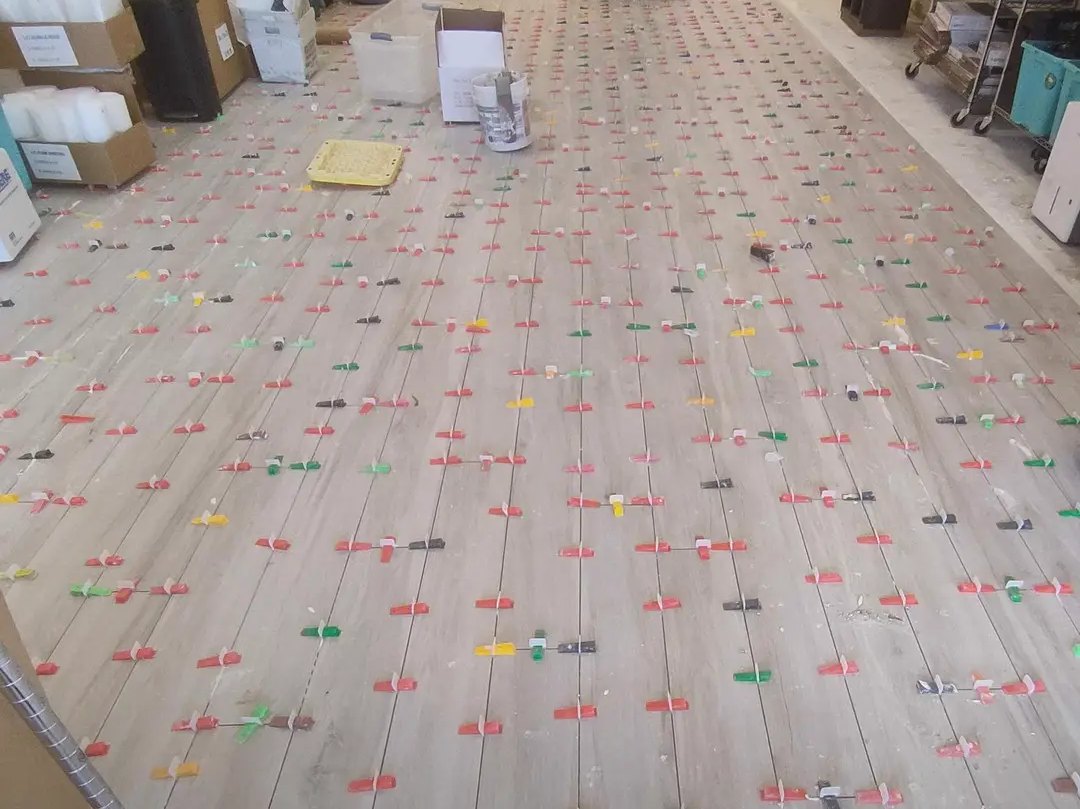 Wood-look tile being installed across a large open floor